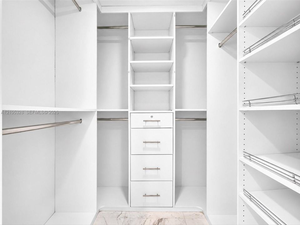 Luxurious custom-designed white closet system featuring generous hanging space, adjustable shelving, and built-in drawers with polished hardware for elegant, organized storage.