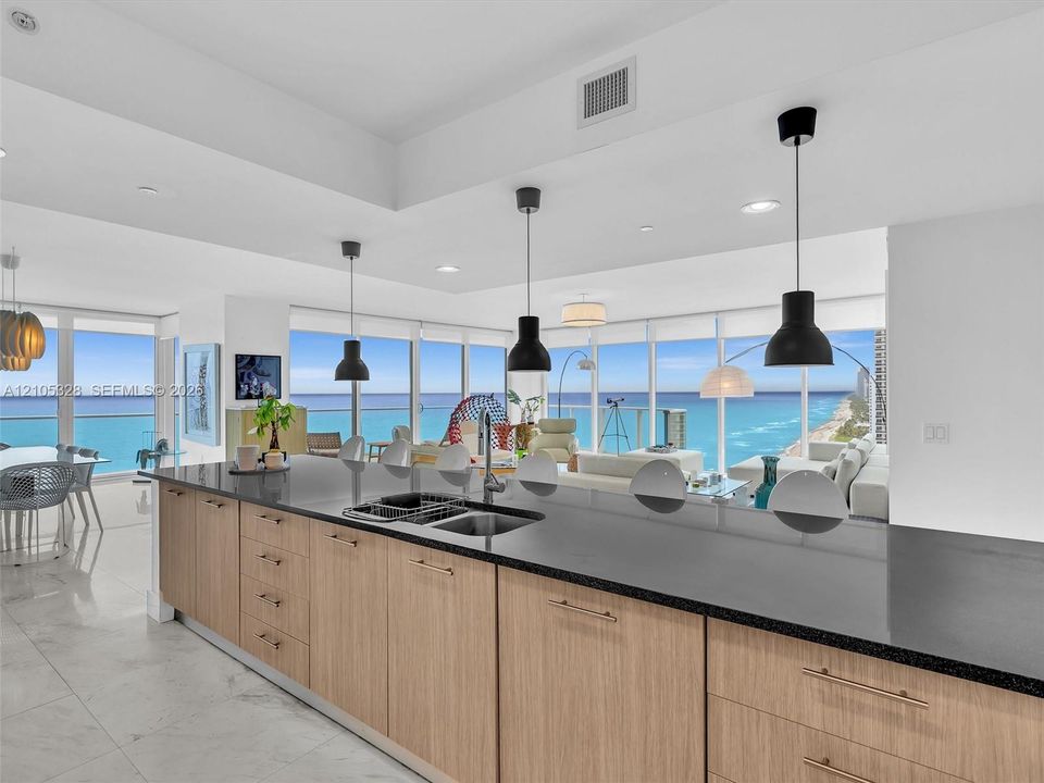 Modern kitchen featuring a spacious center island with a double sink, sleek black countertops, and elegant wood-finish cabinetry.