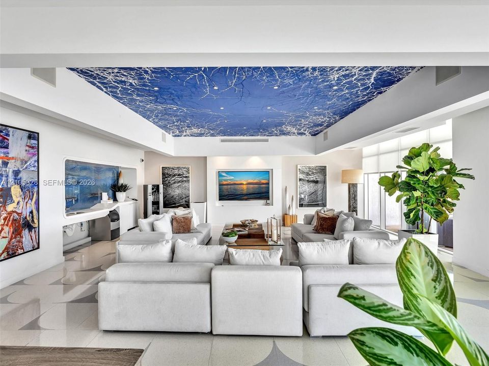 Elegant residents' lounge offering a sophisticated, boutique-style ambiance with artistic blue-and-white ceiling details, integrated speakers, illuminated display niches, and designer tile flooring—a stylish space for residents to relax and socialize.