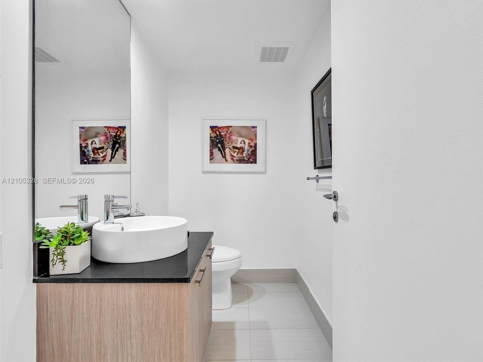 Floating wood-finish vanity with a dark countertop and vessel sink