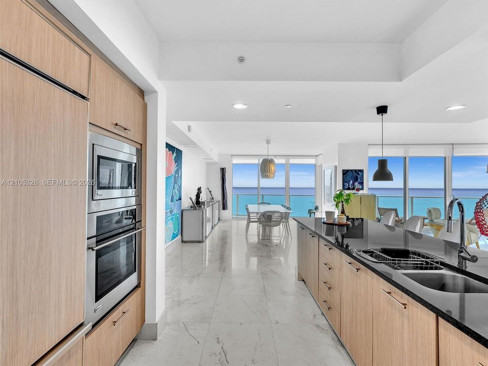 Gourmet kitchen featuring wood-finish cabinetry, stainless steel appliances, and sleek dark stone countertops with an undermount sink.
