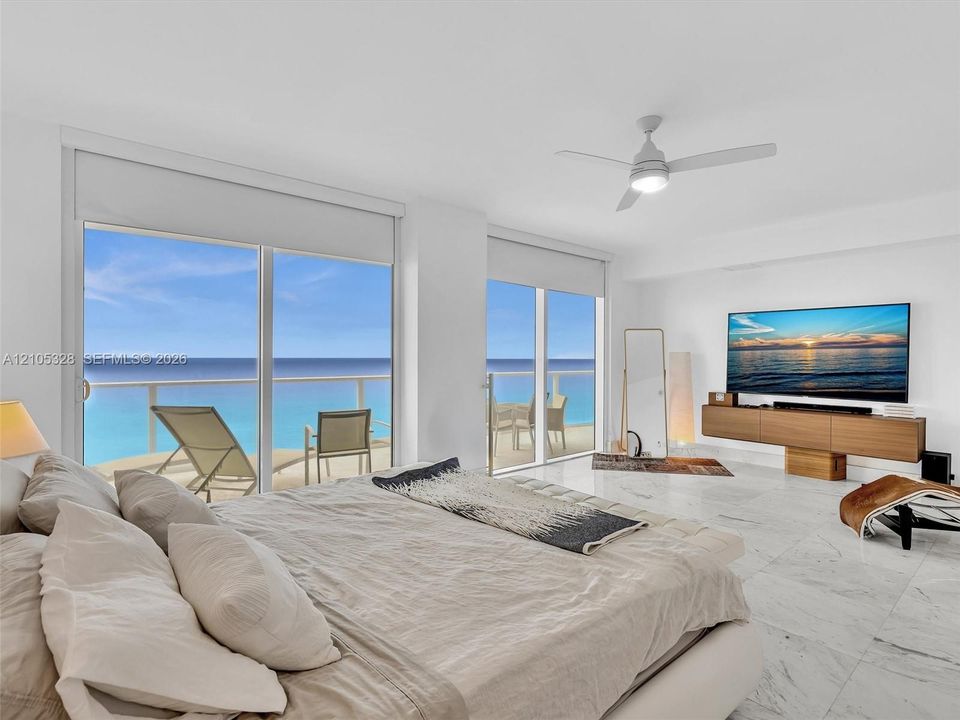 Wake up to breathtaking ocean views from the comfort of your bed in this spacious primary suite, featuring floor-to-ceiling sliding glass doors with direct access to a private balcony.