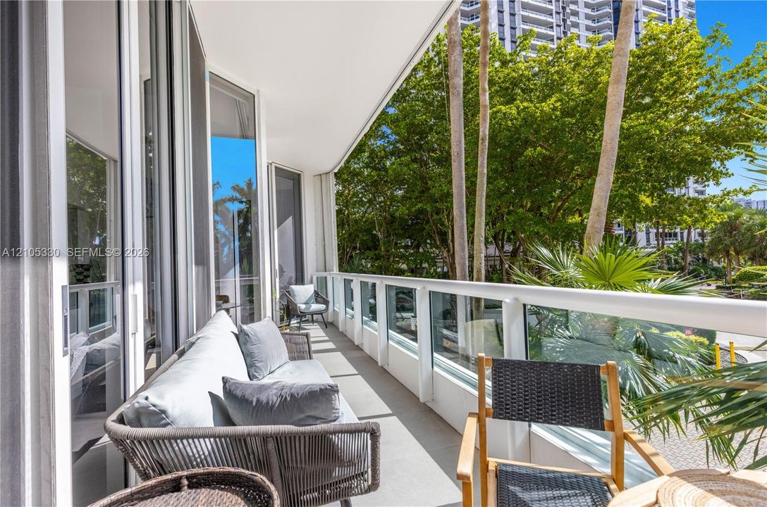 Expansive balcony featuring a glass panel railing system, concrete flooring, and multiple sliding glass doors