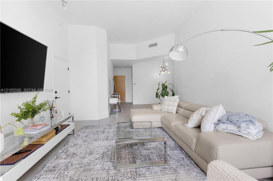 Bright living area featuring high ceilings, light-toned walls, and recessed lighting