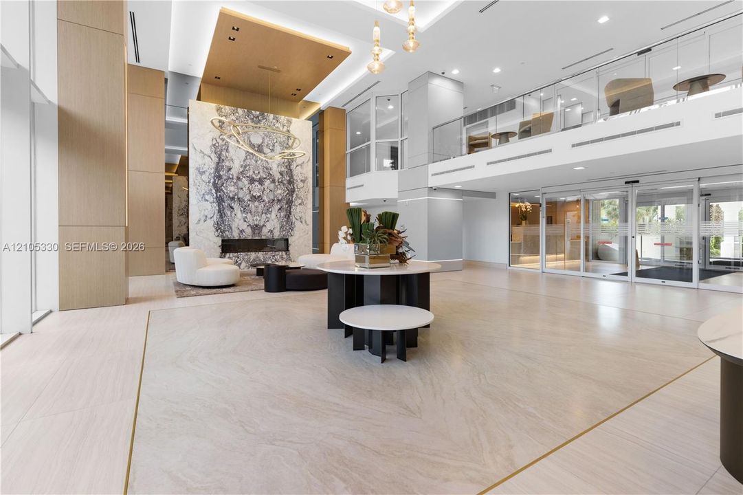 Grand entryway featuring high ceilings, a built-in fireplace with a stone surround, and polished tile flooring