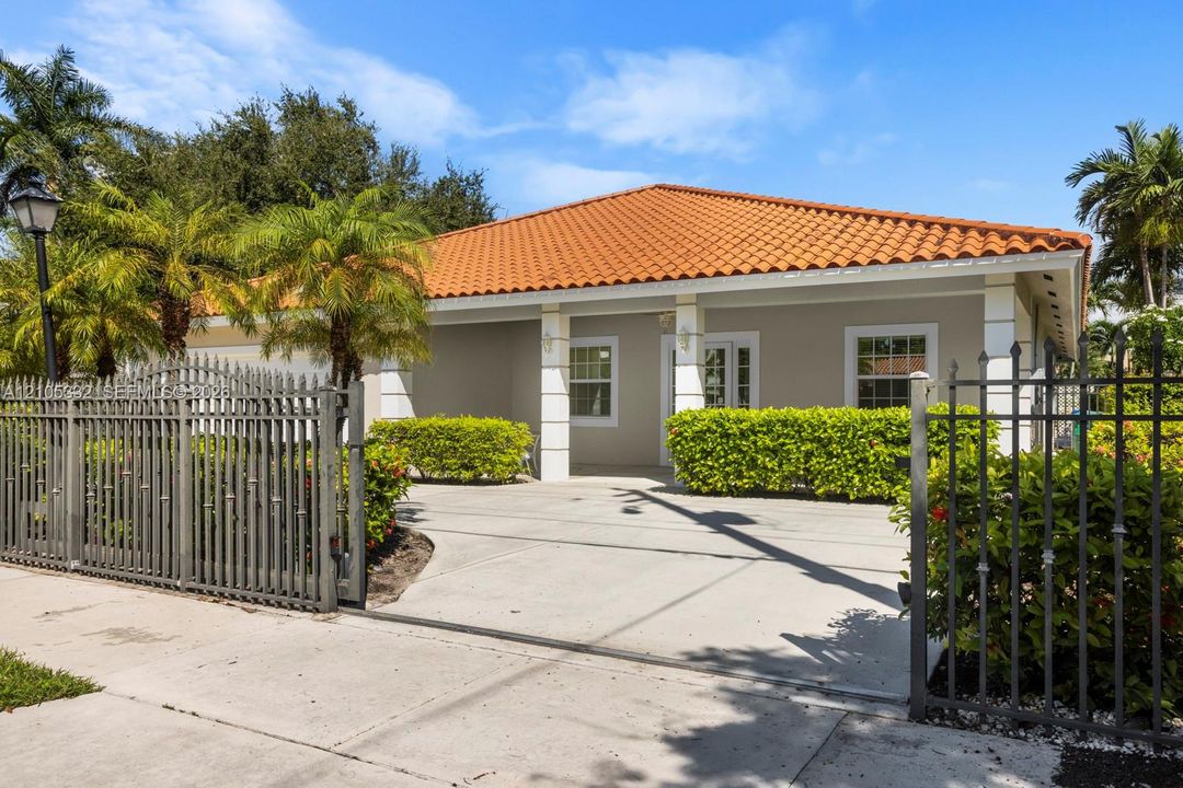 Property features a terracotta tile roof, a light grey exterior, column accents, a decorative security gate, and a paved driveway