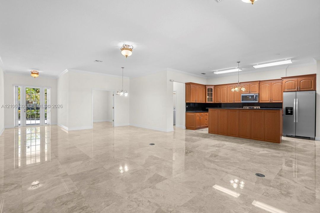 Polished stone-finish flooring throughout, kitchen featuring wood cabinetry and stainless steel appliances, and French doors providing outdoor access