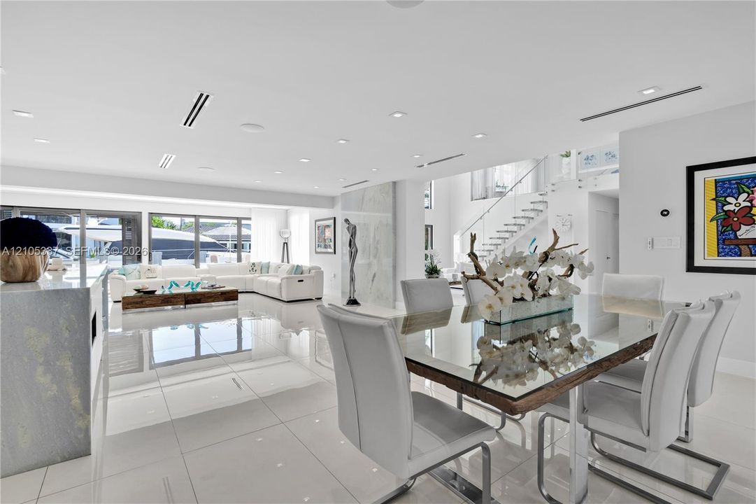 Large-format porcelain tile flooring, recessed ceiling lighting, linear air diffusers, multi-panel sliding glass doors, and a staircase featuring glass panel railings
