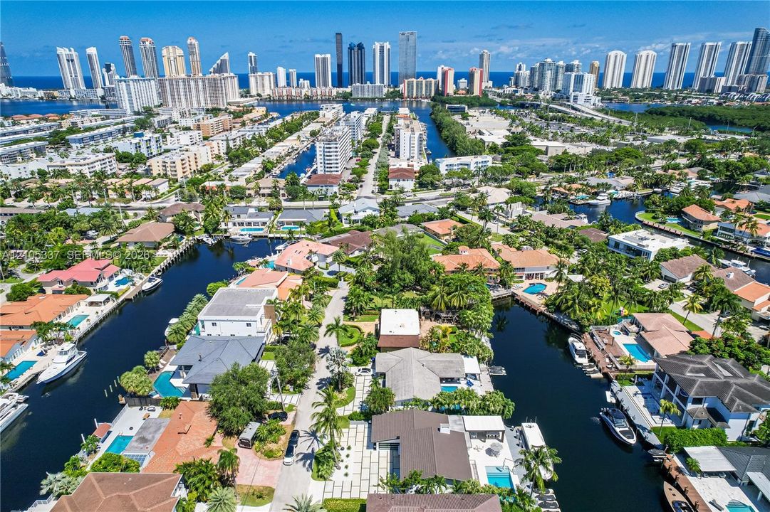Aerial perspective featuring deep-water canal access, private boat dockage, paved multi-vehicle driveway, swimming pool, and tropical landscaping