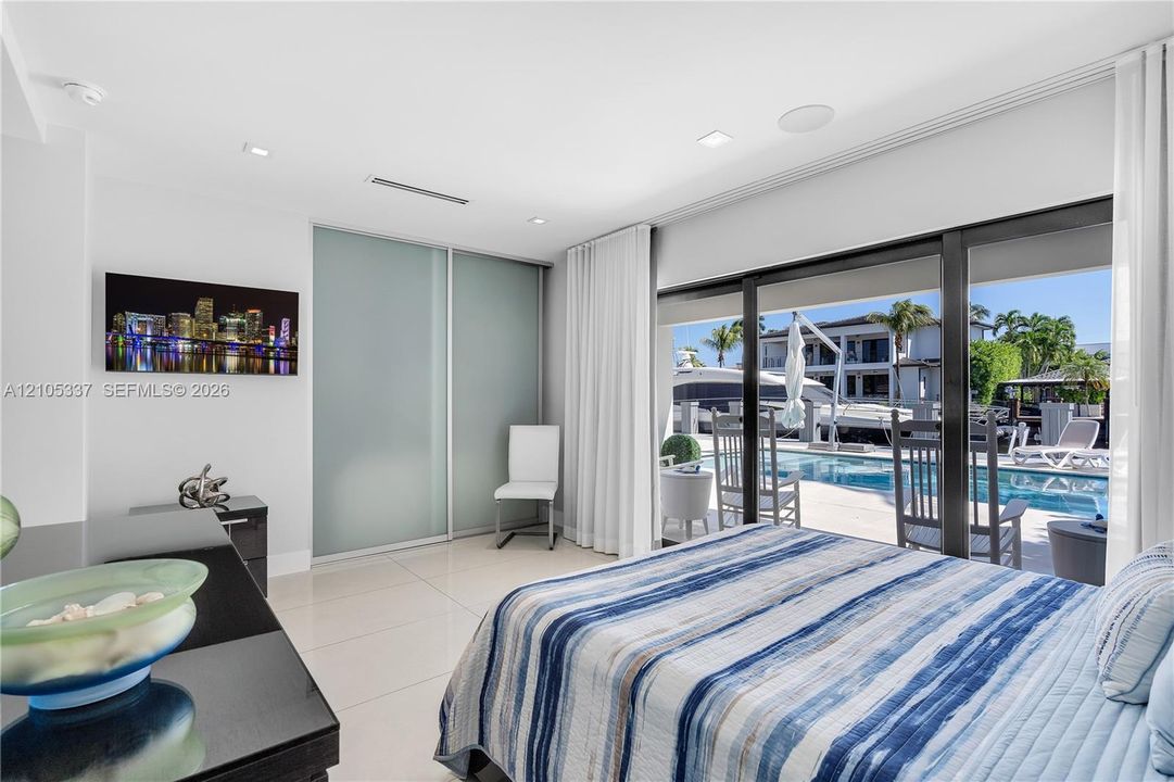 Large-format ceramic floor tiling, floor-to-ceiling glass sliding doors, recessed lighting, and built-in sliding panel closet doors
