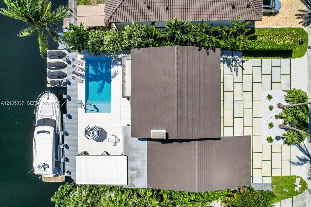 Waterfront property featuring a private boat dock, rectangular in-ground swimming pool, stone-paver hardscaping, and professional landscaping