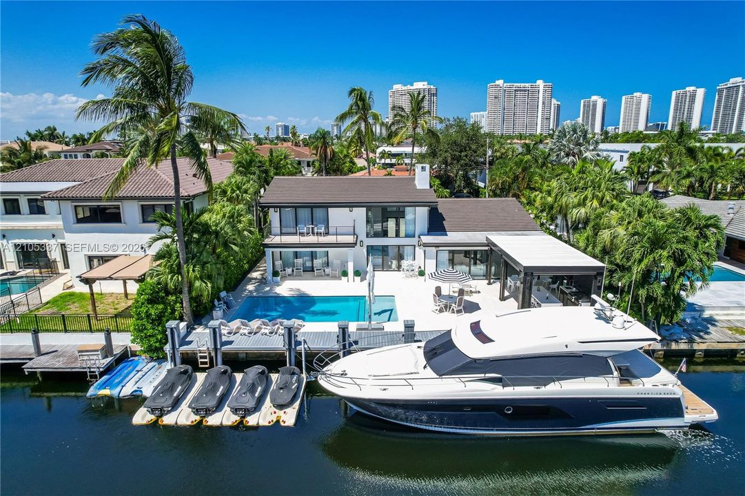 Waterfront property featuring a private boat dock, jet ski lifts, a swimming pool, and a covered patio area