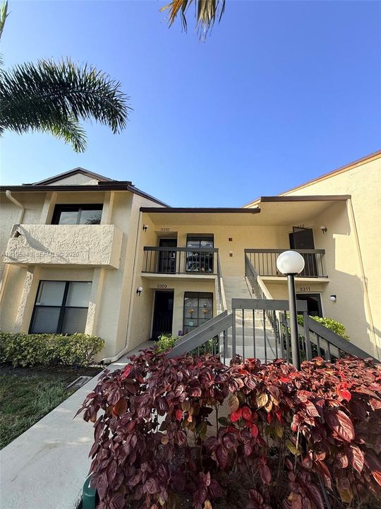 Multi-unit structure featuring a light-colored stucco exterior and dark trim