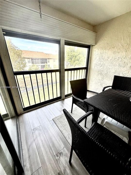 Enclosed balcony featuring wood-finish flooring and a textured wall finish