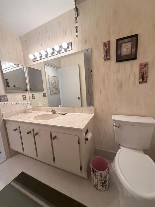Vanity with an integrated sink, built-in cabinetry, wall-mounted mirror, and overhead lighting fixture