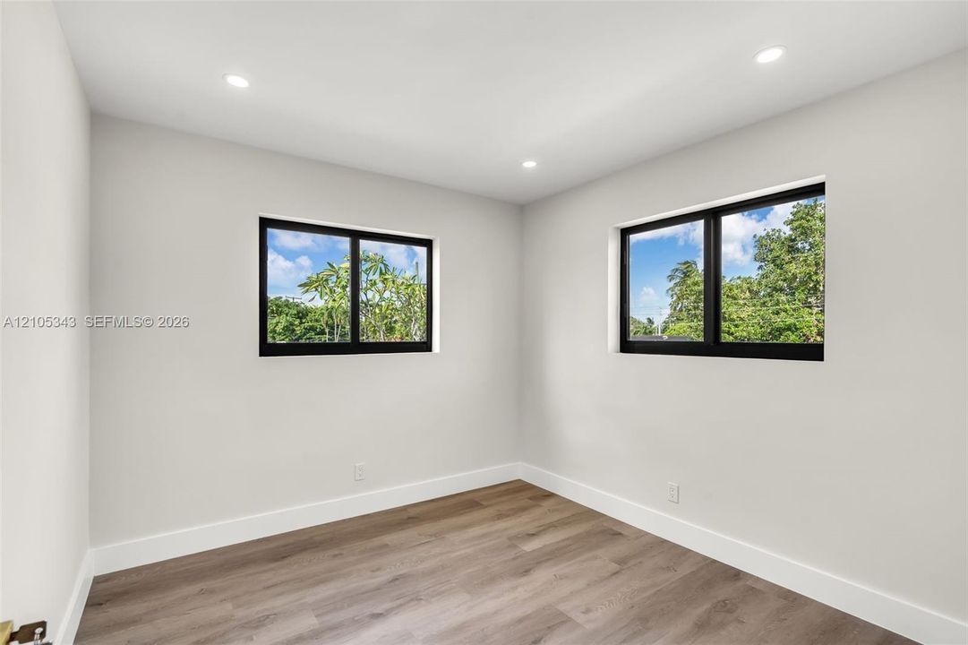 Neutral wall palette featuring wood-finish flooring, recessed lighting, and dual windows with black frames