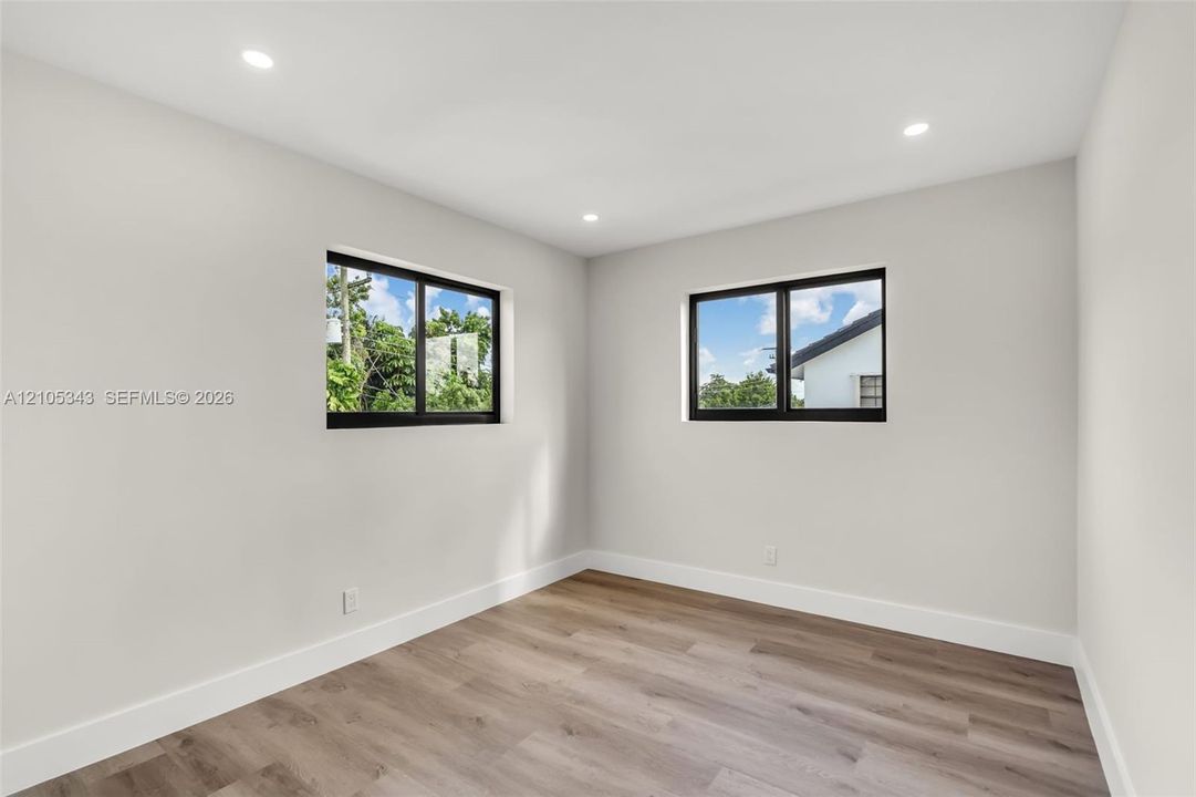 Interior space featuring wood-finish flooring, neutral wall tones, recessed lighting, and dual windows with black frames