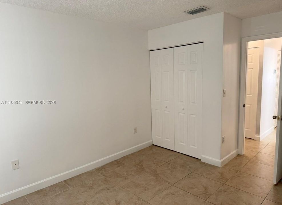 Neutral wall tones, tiled flooring, bi-fold closet doors, and a textured ceiling