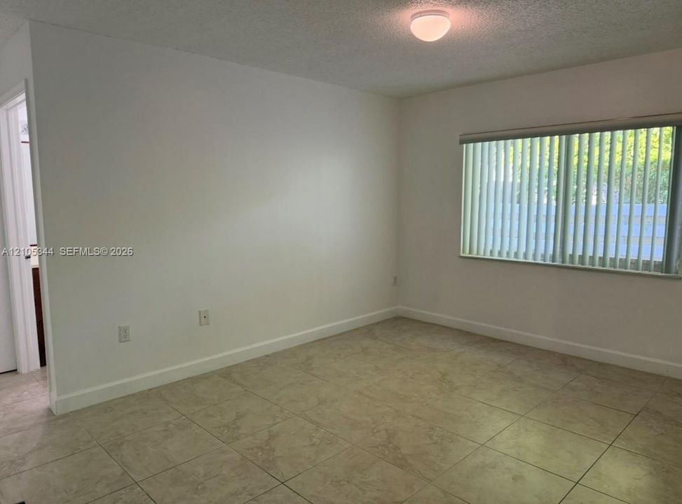 Neutral wall color, ceramic tile flooring, horizontal window blinds, and flush mount ceiling light fixture