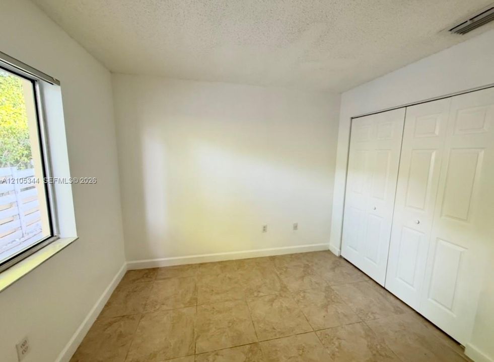 Recessed window with exterior fencing, textured ceiling, and bi-fold closet doors