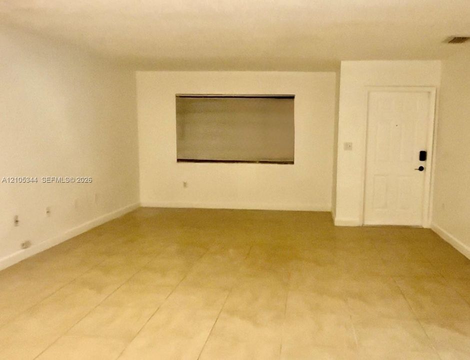 Spacious interior room featuring tile flooring, recessed lighting, and a wall-mounted window with horizontal blinds