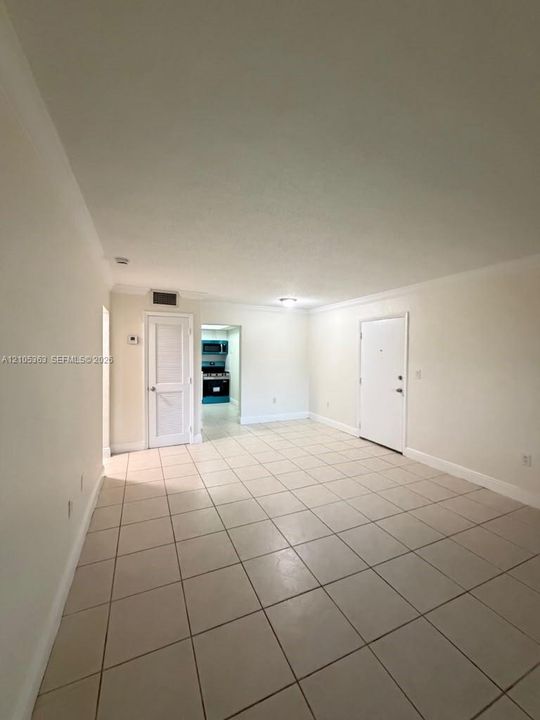 Neutral tone tile flooring, white painted walls, crown molding, and recessed lighting