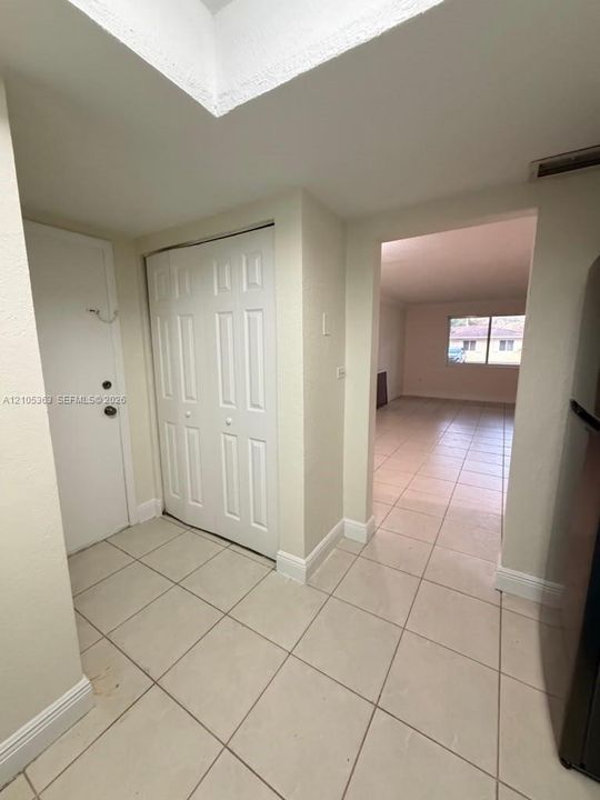 Square tile flooring throughout, featuring a white bi-fold closet door and white trim