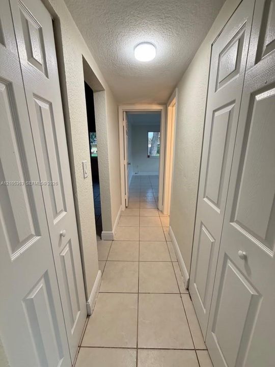 Hallway with neutral tile flooring, flush mount ceiling lighting, and white paneled doors