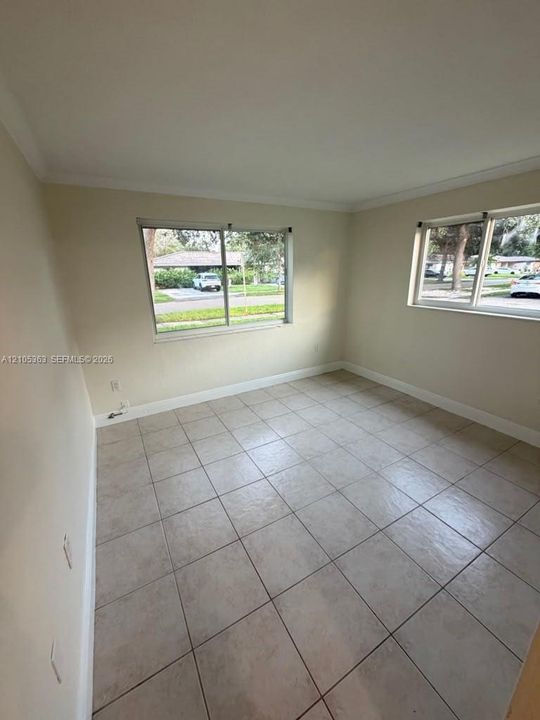 Neutral-toned tile flooring, two windows, and crown molding