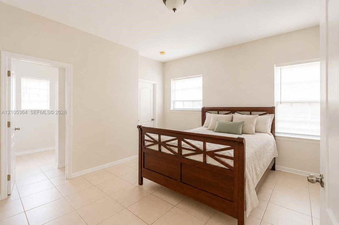 Light-toned tile flooring, two windows with blinds, a ceiling-mounted light fixture, and neutral wall tones