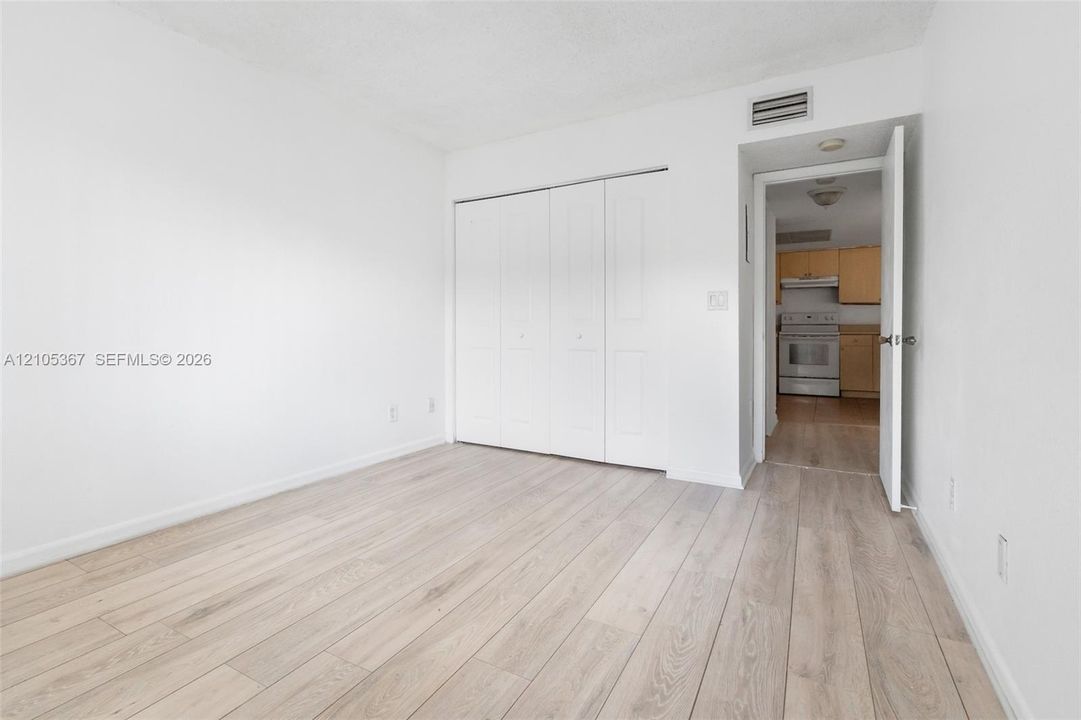 Interior space featuring wood-finish flooring, white walls, and a large reach-in closet with white paneled bi-fold doors