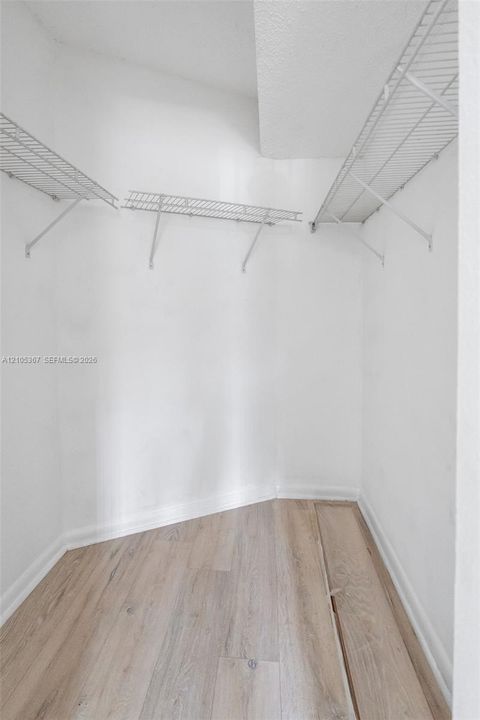 Walk-in storage space featuring wood-finish flooring and white wire shelving