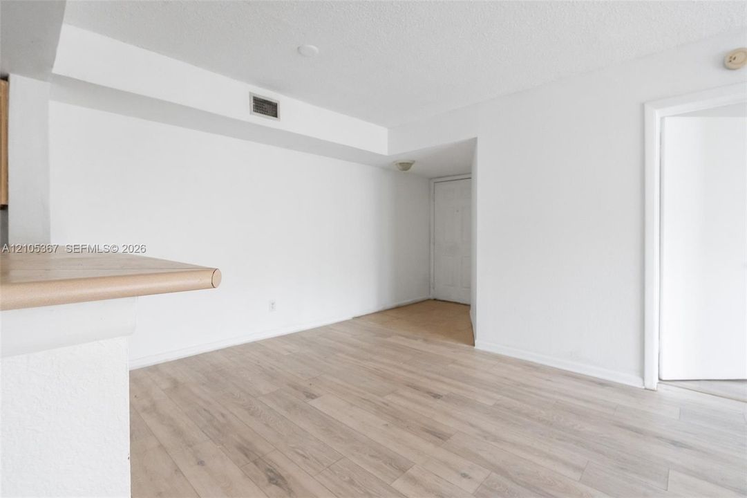 Interior space featuring light-toned wood-finish flooring, neutral wall paint, and a built-in counter surface with a rounded edge