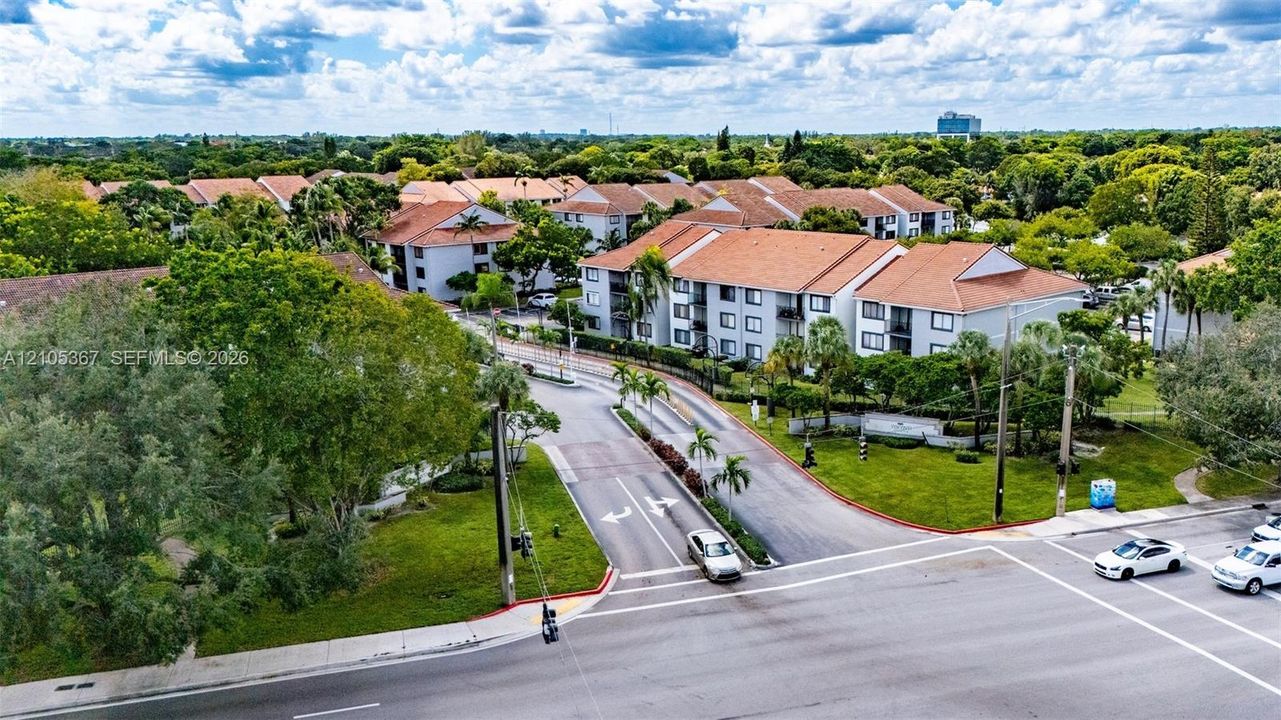 Aerial view of multi-story residential buildings featuring tile roofs, light-toned exterior facades, and extensive landscaping with mature trees and maintained lawns