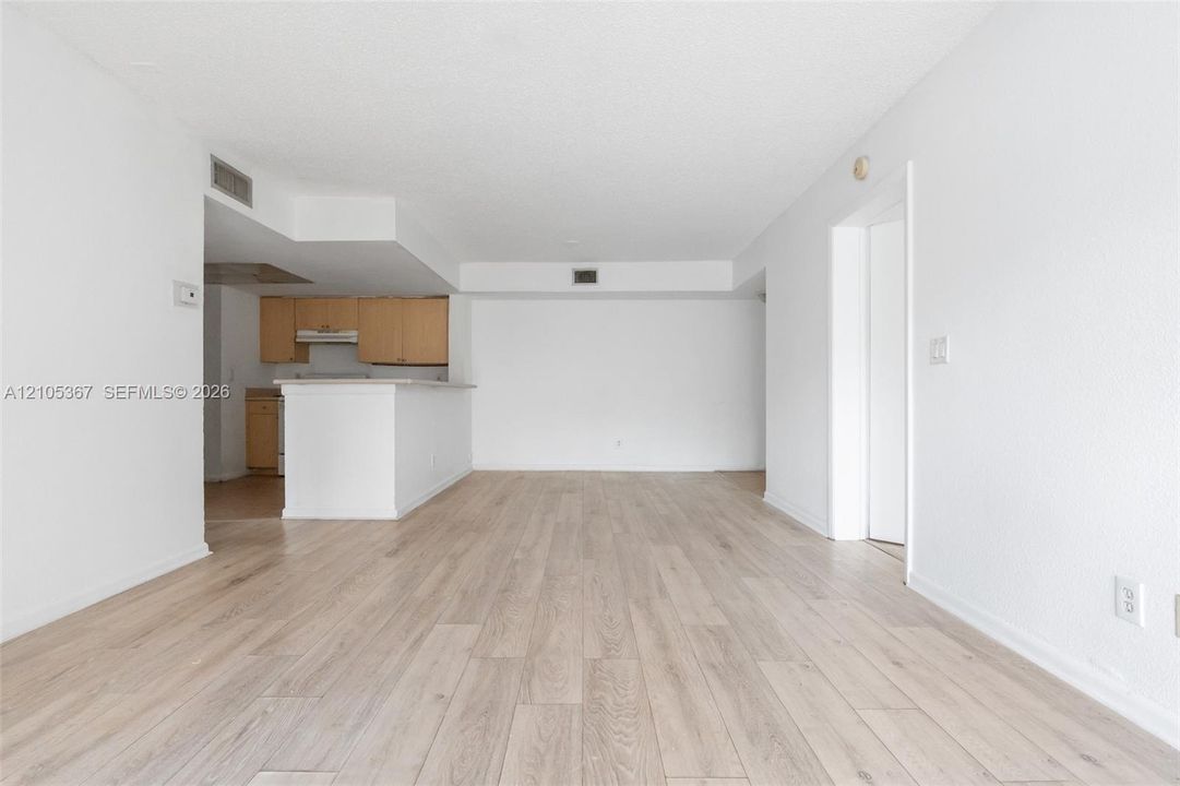 Open-concept interior featuring wood-finish flooring, white walls, and a breakfast bar