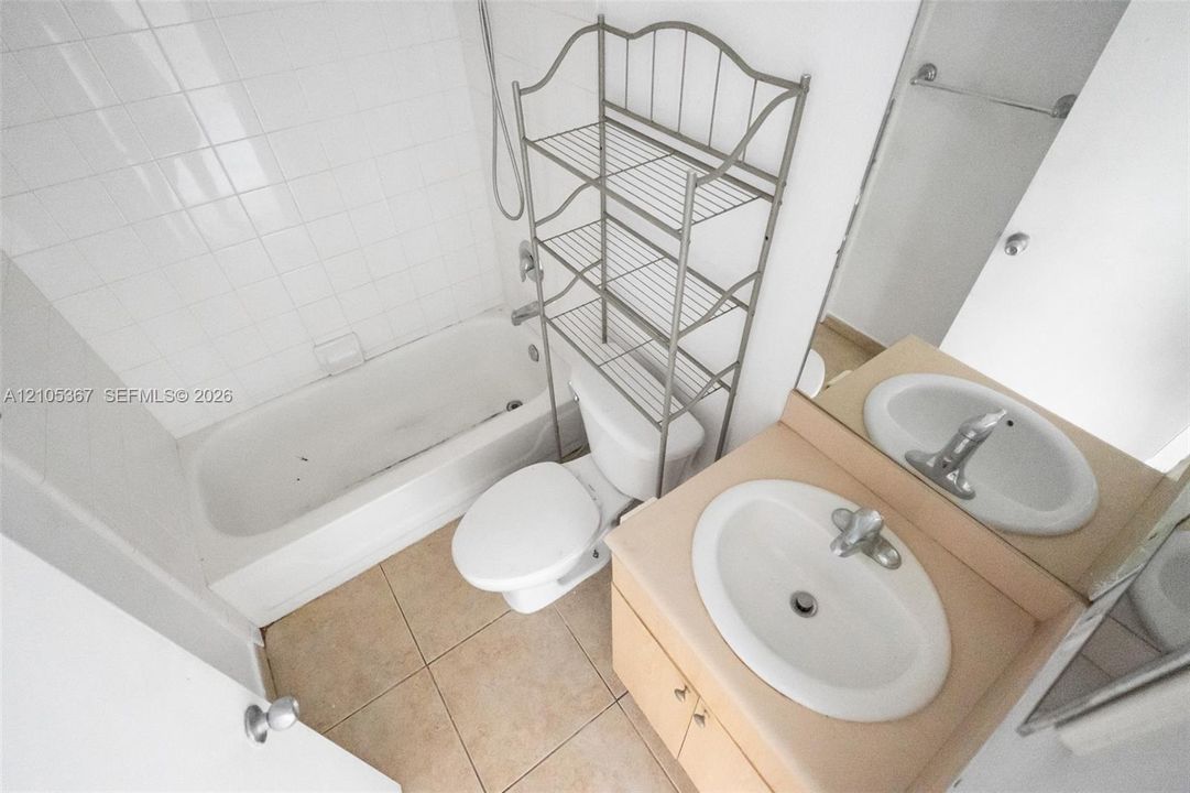Bathroom featuring a shower and bathtub combination with white wall tile, a vanity with an integrated oval sink, and ceramic floor tile