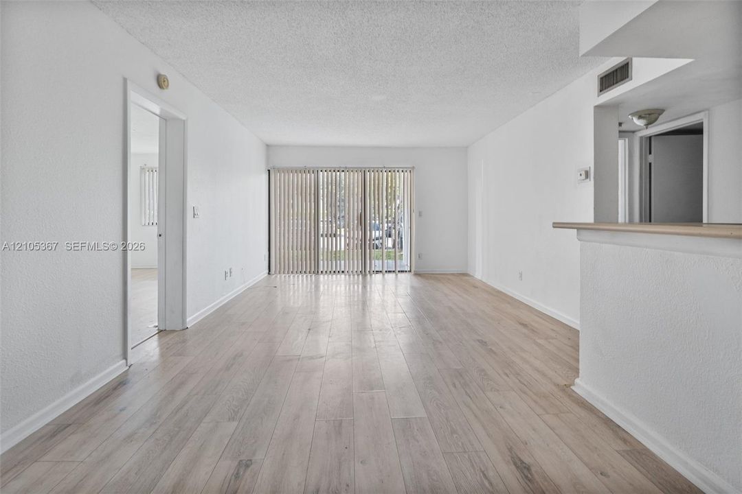Interior space featuring wood-finish flooring, textured ceilings, and a sliding glass door with vertical blinds
