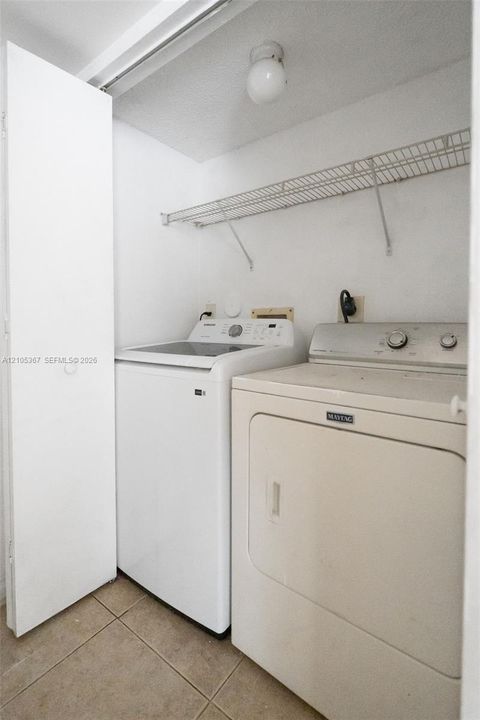 Utility area featuring ceramic tile flooring, built-in wire shelving, and a ceiling-mounted globe light fixture