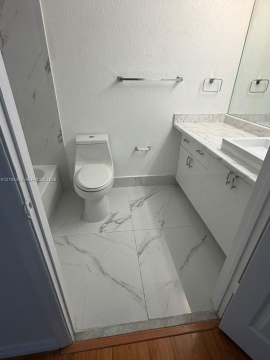 White vanity with a rectangular basin, white countertop, and chrome hardware
