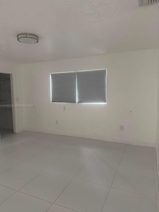 White tile flooring, white walls, and a flush-mount ceiling light