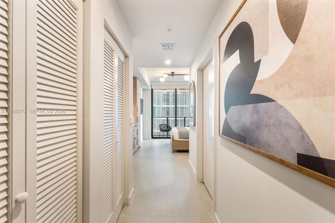 Hallway featuring louvered bi-fold doors, recessed lighting, and light-toned flooring
