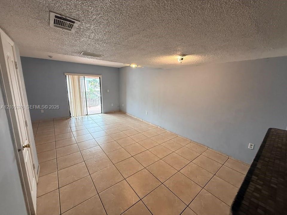 Tile flooring, sliding glass door, overhead lighting, textured ceiling, light blue wall paint