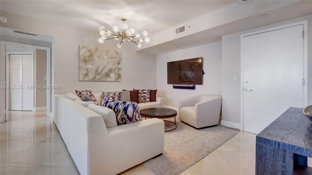 Recessed lighting and a modern chandelier illuminate the living area