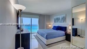 Floor-to-ceiling glass doors, water scenery, wall-mounted television, and a built-in nightstand