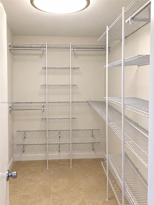 Customizable wire shelving system with multiple storage rods, recessed ceiling light, and tile flooring