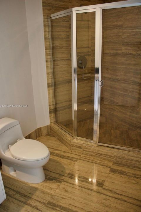 Glass-enclosed shower with polished chrome fixtures
