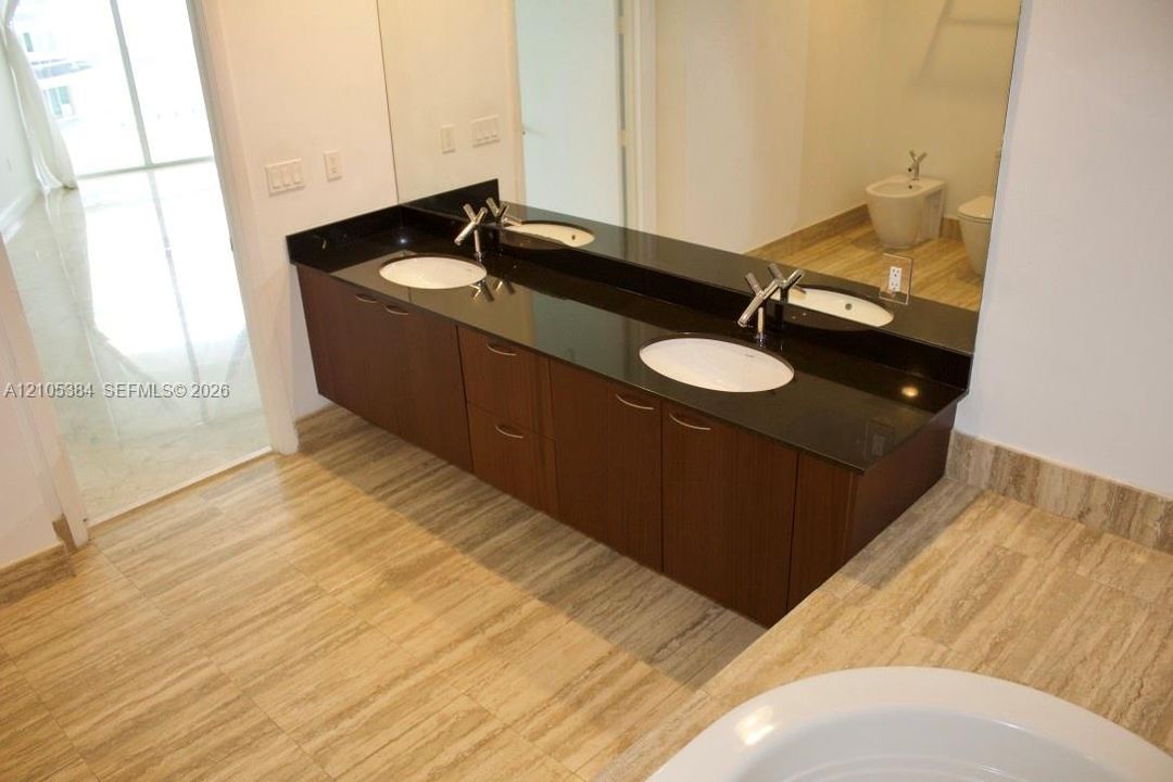 Dual sink vanity with dark wood-finish cabinetry and a black countertop