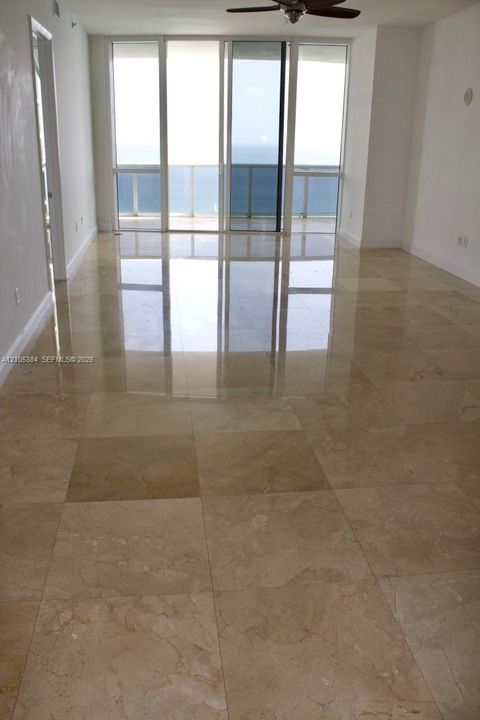 Expansive polished tile flooring with natural light from floor-to-ceiling windows