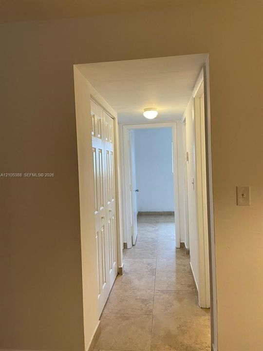Hallway featuring light-toned tile flooring, flush mount lighting, and white paneled doors