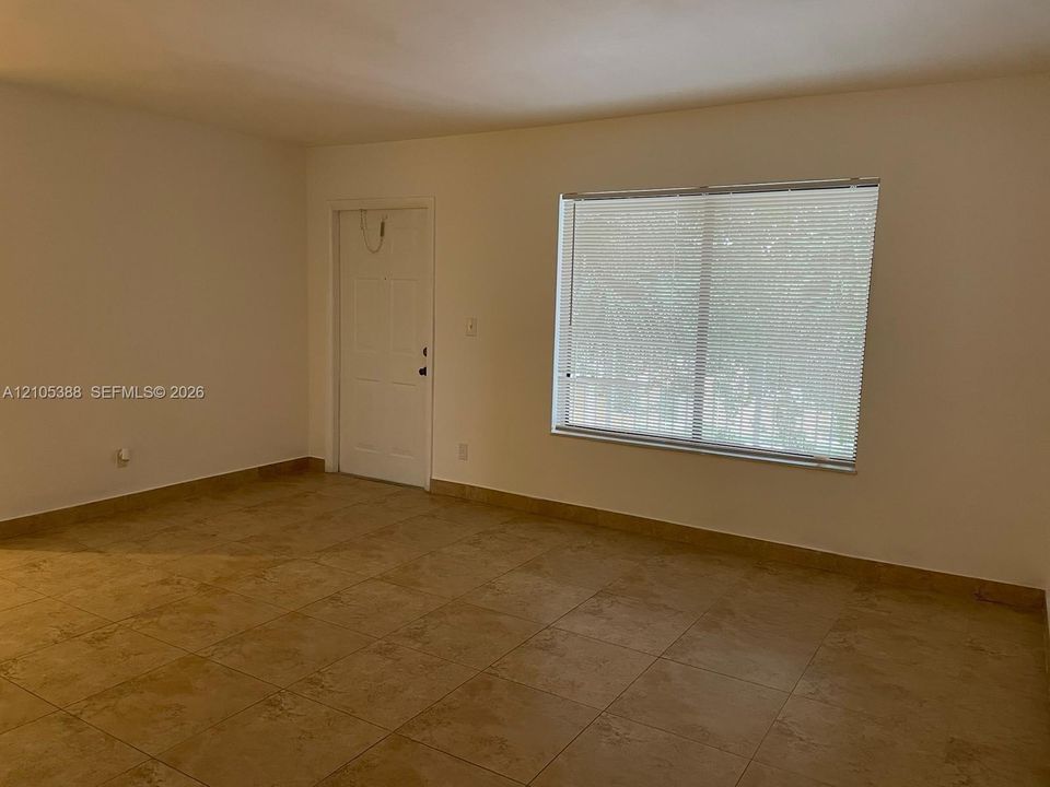 Neutral wall paint, tile flooring, and a window with blinds